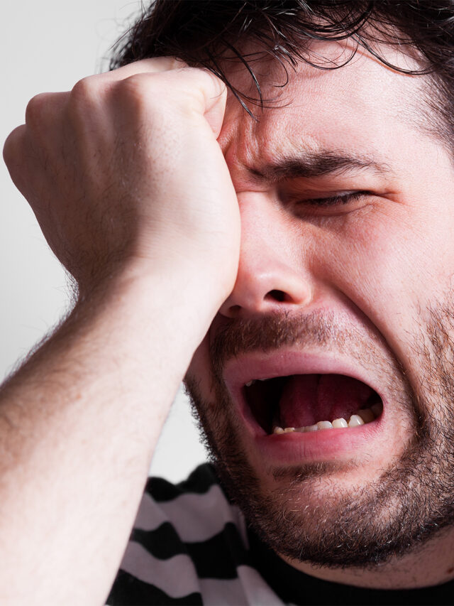 A man wearing a black and white shirt cries out in pain